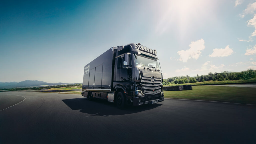 Schwarzer Mercedes-Lkw fährt bei Sonnenschein auf einer Rennstrecke, moderne Technik und Design im Fokus.