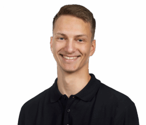 Porträt eines lächelnden Mannes in schwarzem Hemd vor weißem Hintergrund.