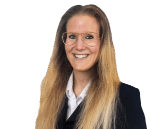 Eine lächelnde Frau mit blonder, langer Frisur und Brille im Business-Outfit vor neutralem Hintergrund.