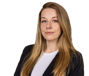 Eine lächelnde Frau mit langen blonden Haaren in Business-Kleidung vor weißem Hintergrund.
