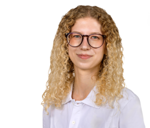 Eine Frau mit lockigem Haar und Brille lächelt in die Kamera, vor weißem Hintergrund.